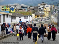 Habitantes locais que deixam os mercados dos animais e encabeçam atrás ao centro de Otavalo. Equador, América do Sul.