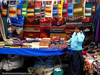 Bolsas padronizadas coloridas, suspensões de parede e chapéus em mercado de Otavalo. Equador, América do Sul.