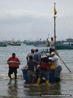 Pescadores que tiram barco em Porto Lopez. Equador, América do Sul.