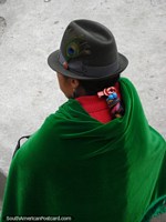 Uma mulher indïgena usa um chapéu com pena e xale verde em Banos. Equador, América do Sul.
