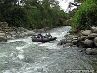 A family go tubing down the Mindo River, 7 tubes joined by rope. Ecuador, South America.