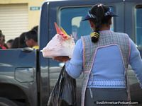 Woman carries tub of ice-cream and cones to sell in Quito streets. Ecuador, South America.