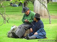 Man and woman sit on grass in park La Alameda in Quito.