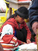 Woman with black hat sells produce at Vilcabamba markets. Ecuador, South America.