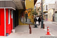 Man in a suit, wall mural in Ambato, 2 men walk past. Ecuador, South America.