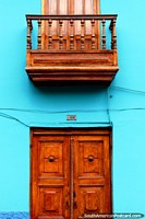 A entrada de madeira esplêndida e o balcão estabelecem-se sobre uma parede azul em Guaranda. Equador, América do Sul.