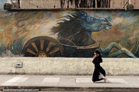 Mural enorme caballo, una mujer vestida de negro camina pasado, Riobamba. Ecuador, Sudamerica.
