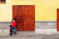 Quechua woman and son in hats walk along the street in Alausi. Ecuador, South America.