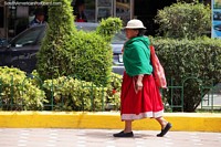 Uma mulher local em passeios verdes e vermelhos ao longo da rua em Alausi. Equador, América do Sul.