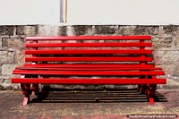Um banco vermelho-vivo senta-se em de Mayo Plazoleta 24 em Alausi. Equador, América do Sul.