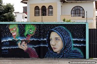 A woman holds 2 green ghosts in her hand, mural near the stadium in Cuenca. Ecuador, South America.