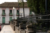An old building, lamps and fence around the plaza in Pujili.