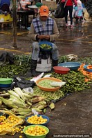 Una mujer extrae los guisantes de las vainas y vende bolsas de guisantes en el mercado de Saquisilí. Ecuador, Sudamerica.