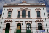 Versión más grande de Edificio histórico de 1919 en Ibarra, ventanas arqueadas y colores pálidos.
