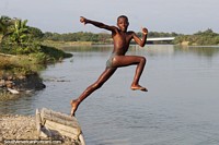Um pulo gigantesco da humanidade, o rapaz jovem pula no rio em Esmeraldas. Equador, América do Sul.