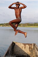 Grande pose aérea, rapaz que salta de uma canoa na água no Rio Esmeraldas. Equador, América do Sul.