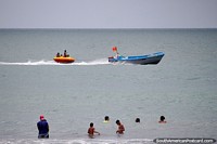 Niños cabalgando en un bote inflable remolcado, diversión en la playa de Atacames. Ecuador, Sudamerica.