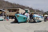 Pescadores e os seus barcos na aldeia na praia em El Matal. Equador, América do Sul.