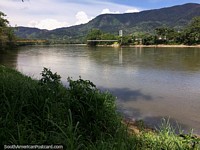Junto do Rio de Zamora em Yantzaza, ponte distante, águas calmas e colinas verdes. Equador, América do Sul.