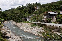 Ecuador Photo - Wooden houses scattered among thick trees on the hillside at the river in Limon.