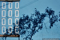 Ecuador Photo - Light blue facade, checkered wooden door and fantastic shadow of a tree in Banos.