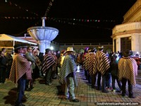 Reunión de gente local en Latacunga por la noche, hombres con chales y sombreros tradicionales. Ecuador, Sudamerica.