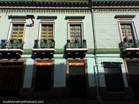 Fachada histórica de madera con puertas verdes y balcones de hierro, Quito central.
