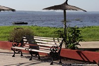 rea de csped con sombrillas de paja y asientos junto al lago Ypacarai en Aregua. Paraguay, Sudamerica.