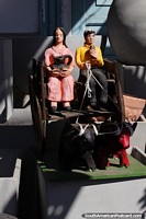 Hombre y mujer sentados en un carro tirado por vacas, arte hecho en Aregua. Paraguay, Sudamerica.