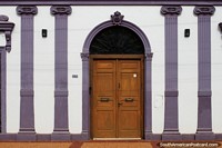 Decorated building facade with ceramic columns and arched wooden door in Concepcion. Paraguay, South America.
