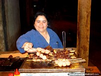 Uma senhora cozinhando espetinhos de bife e linguiça em uma rua de Ybycui. Paraguai, América do Sul.