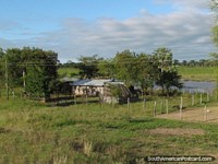 Pequena propriedade rural e casa de madeira junto da água perto de Mondelindo, Gran Chaco. Paraguai, América do Sul.