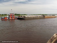 O rebocador laranja 'Don Manuel' empurra a barcaça 'Leticia' no rio Paraguai, em Concepcion. Paraguai, América do Sul.
