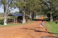 A woman begins her walk down a long dirt road in the countryside, north of Villarrica. Paraguay, South America.