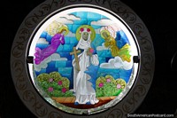 Larger version of Woman holds a cross and a book, angels fly overhead, stained glass window at Cathedral San Blas in Ciudad del Este.