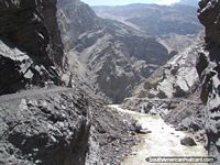 Río que corre en medio de terreno dentado gris y negro de Chuquicara a Caraz. Perú, Sudamerica.