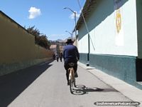 O homem anda em uma bicicleta abaixo a rua em Yunguyo. Peru, América do Sul.