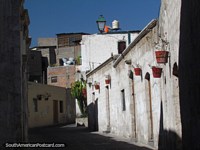 Pasajes peatonales estrechos entre casas con macetas en barrio San Lazaro en Arequipa. Perú, Sudamerica.