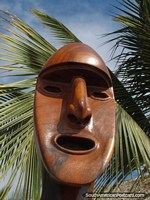 Carved wooden face and palm leaves in Mancora. Peru, South America.