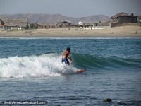 A young local surfer rides a wave at Mancora. Peru, South America.