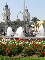 La catedral de Lima detrás de una cama de flores rojas y blancas y una fuente. Perú, Sudamerica.