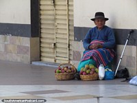 Uma mulher vende frutas de um par de cestas em uma rua de Tacna. Peru, América do Sul.
