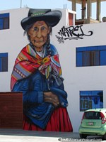 Pintura mural fantástica y enorme de una mujer indígena con telas tradicionales y sombrero en Tacna. Perú, Sudamerica.
