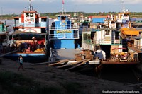 Cargo boats and tugboats get loaded for river travel, Ucayali River, Pucallpa. Peru, South America.