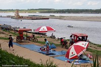 Setting up riverside stalls as a tugboat comes down river in Pucallpa. Peru, South America.