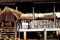Young boy climbs along the balcony of his wooden house in the Amazon between Pucallpa and Aguaytia. Peru, South America.