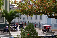 Larger version of View from the plaza towards the church in Yurimaguas, mototaxis and motorbikes.