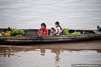 Peru Photo - Family on a wooden river canoe with bananas to sell or eat themselves, the Amazon.