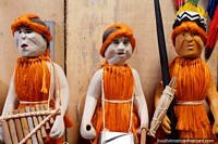3 figures in orange carrying different items, Anaconda Arts Center, Iquitos. Peru, South America.