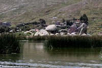 Versión más grande de Grupo de grandes rocas vistas en bote desde Puno a las islas flotantes.